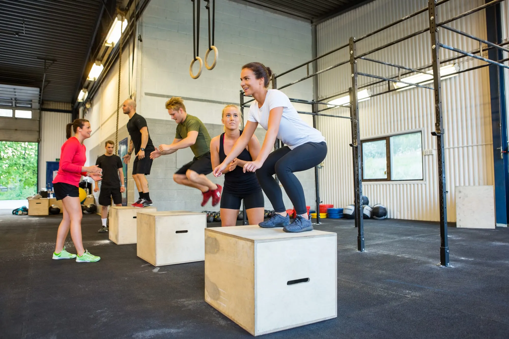 Groupe réalisant des sauts sur des box dans un espace de CrossFit.