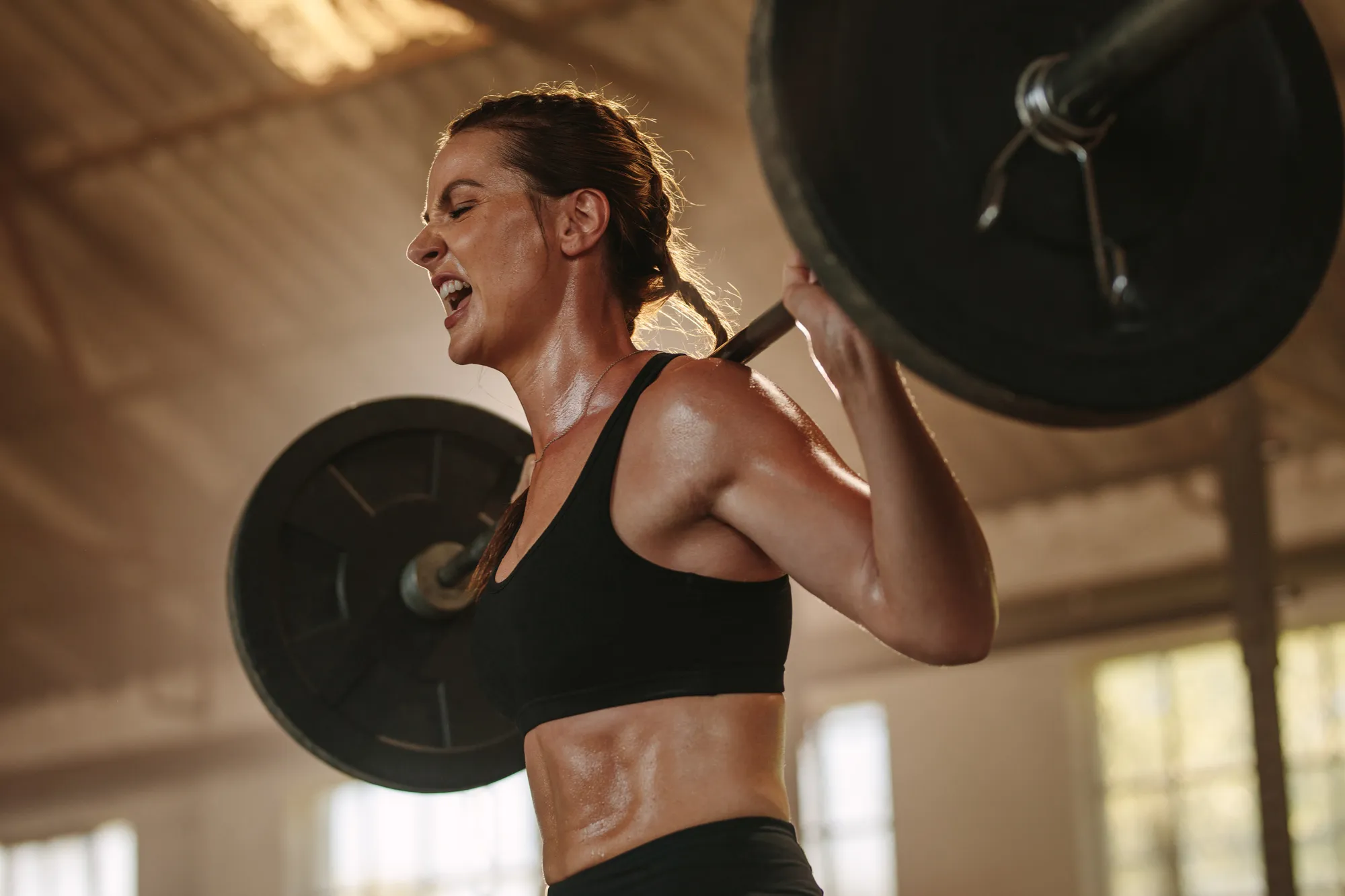 Sportive réalisant un squat avec une barre chargée sur les épaules.