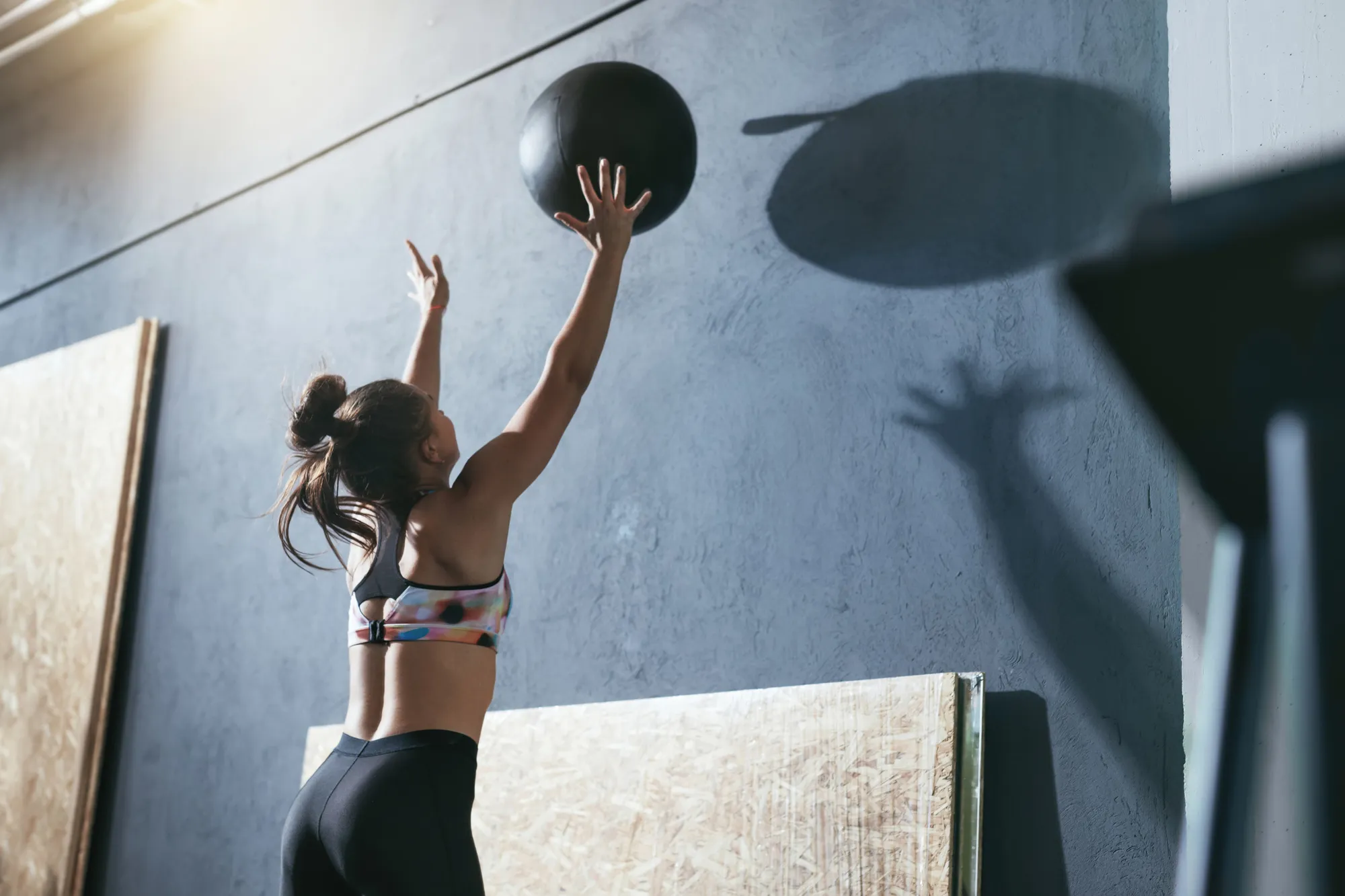 Sportive lançant un ballon lesté contre un mur pendant un exercice.